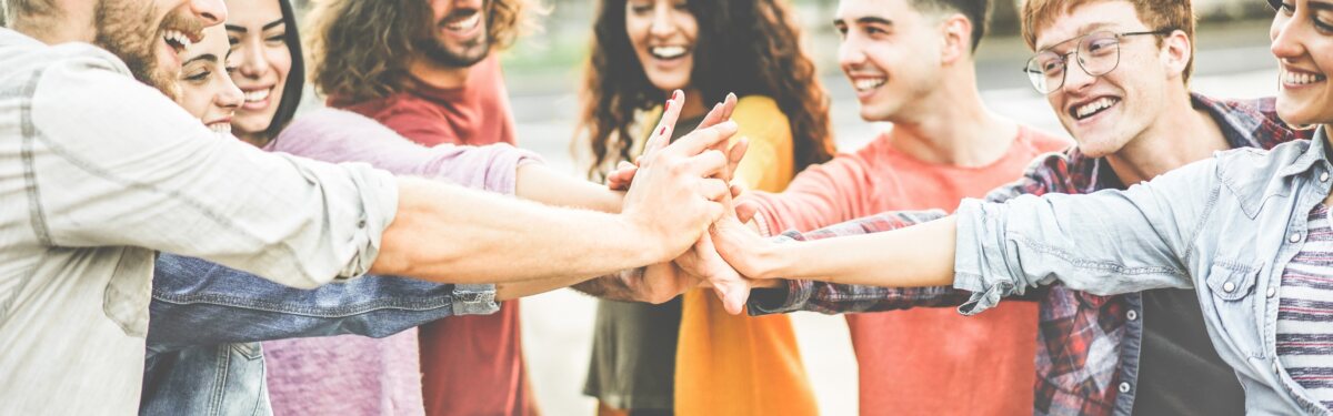 Young happy people stacking hands outdoor 